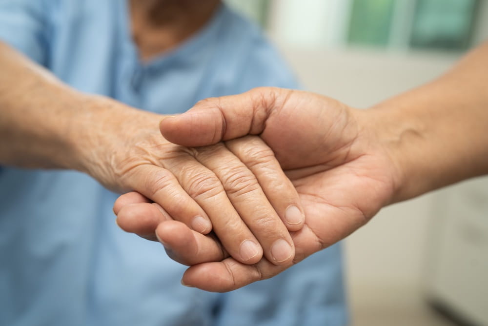 Caregiver holding hand of elderly woman patient