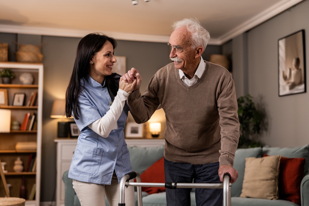 Young caregiver is helping senior man to walk
